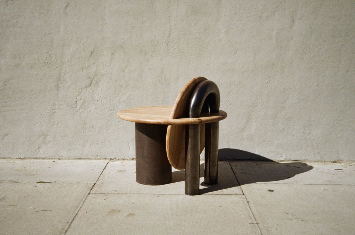 Raw mini stool from behind, a steel tube arch looping over the backrest