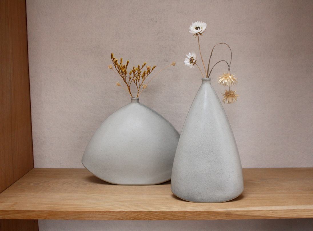 Both vases holding dried flowers on an oak shelf