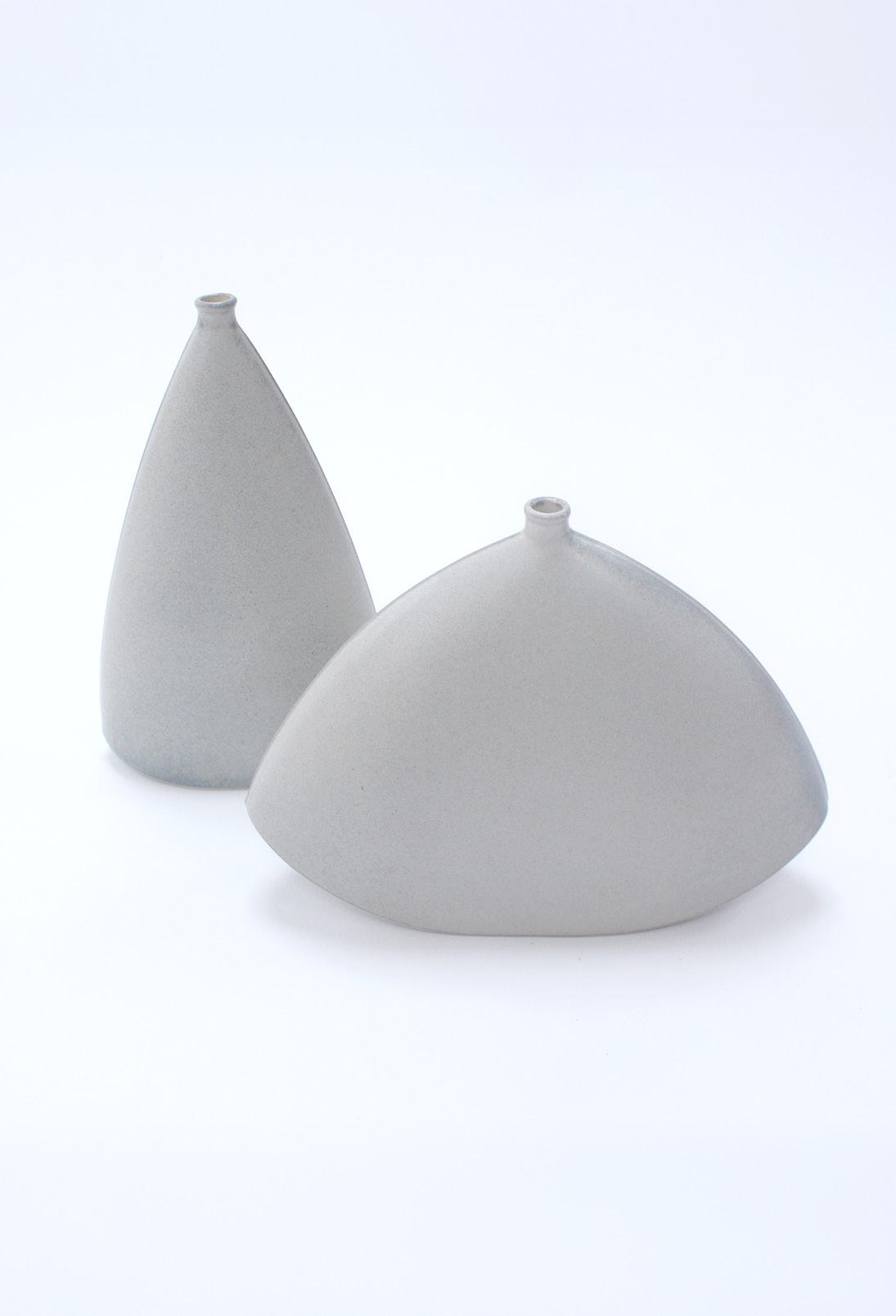 Two pale grey ceramic vases, one tall cone and one wide dome