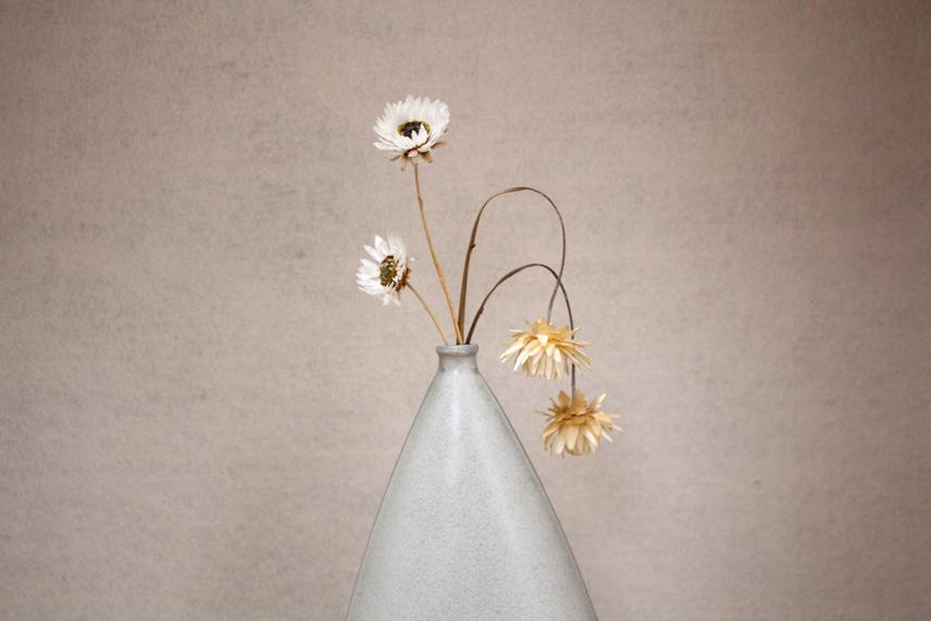 Dried flowers in the neck of the tall vase