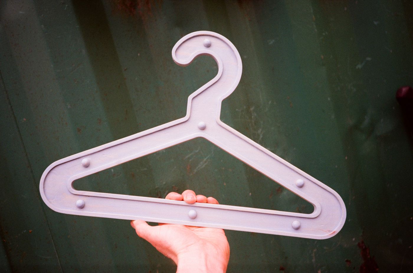 Lilac Girder Hanger held up against a green shipping container