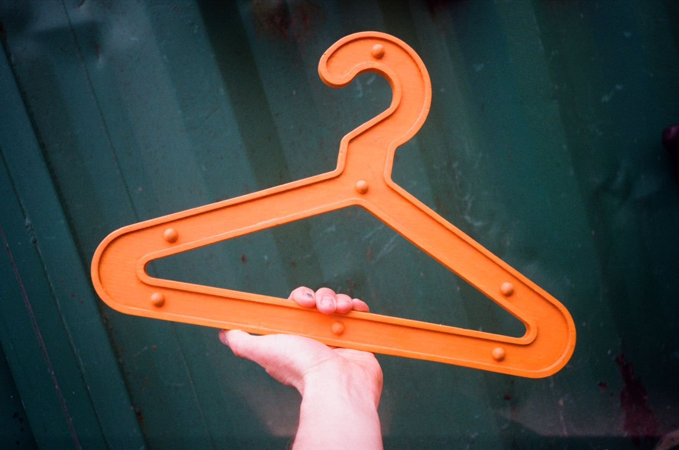 Orange Girder Hanger held up against a green shipping container