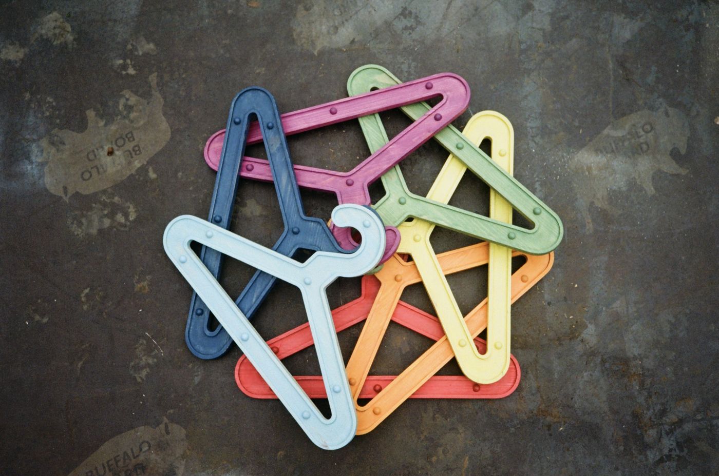 The full set of coloured Girder Hangers piled on a weathered steel floor