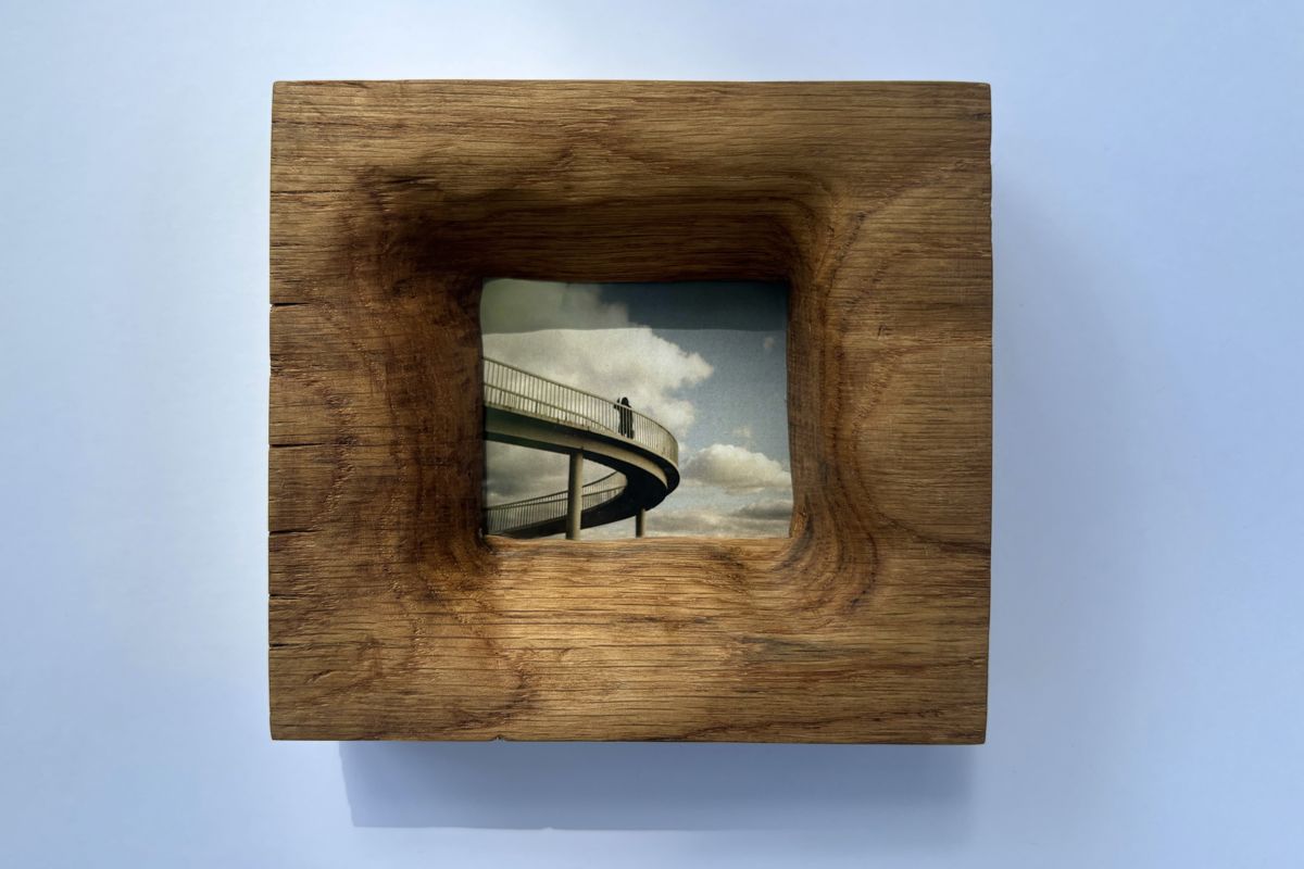 Oak frame holding a photo of a spiral footbridge against clouds