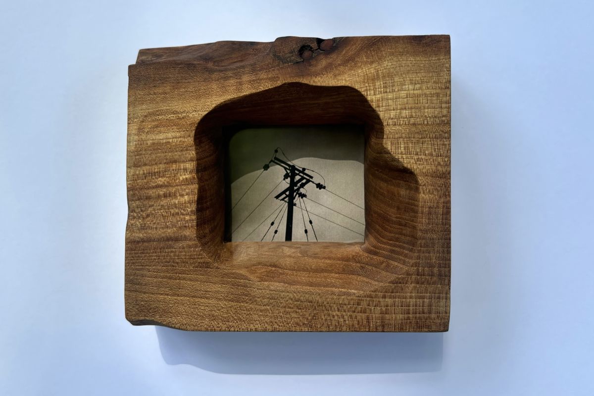 Live-edge hardwood frame with an arched opening, holding a telegraph pole photo
