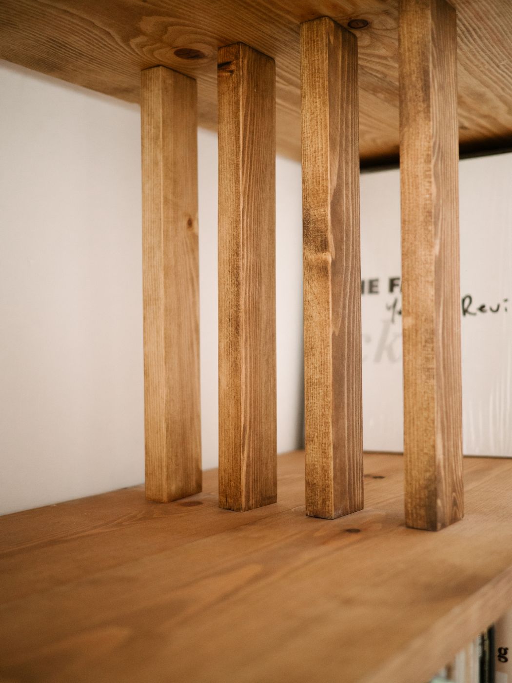 Four square posts between two shelves, grain in detail