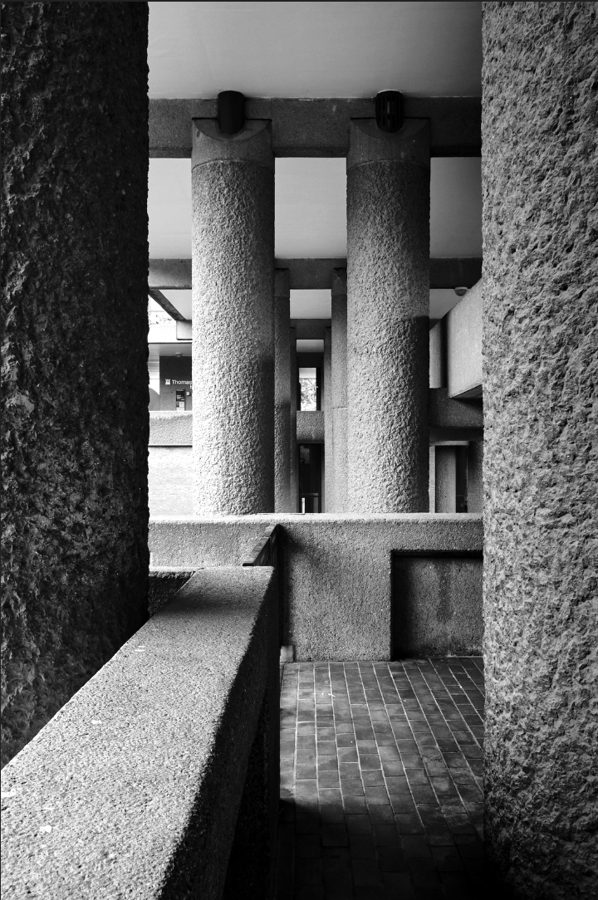 Rows of rough concrete columns beneath a brutalist walkway