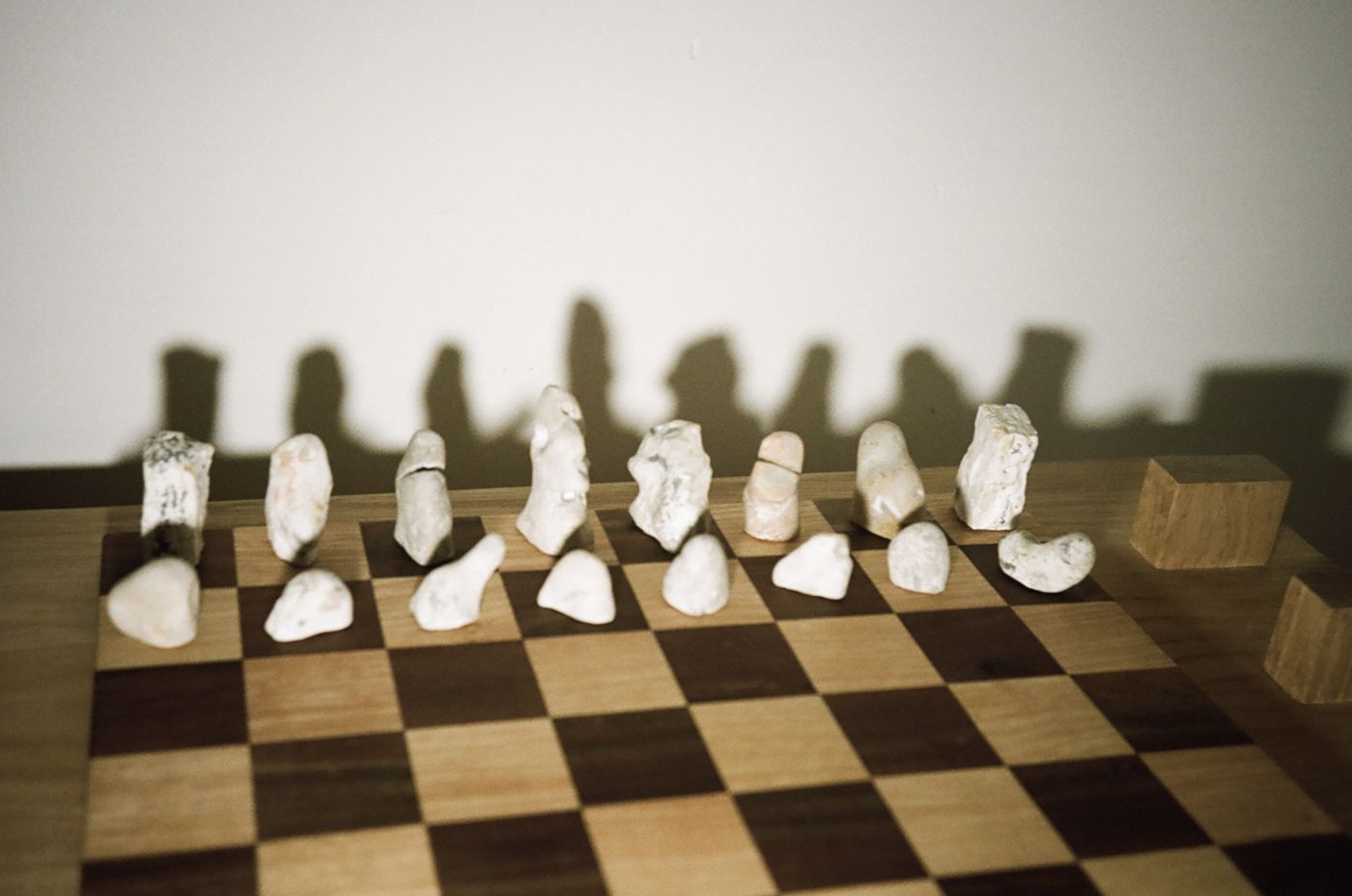 Pale chalk pieces lined up on the board, their shadows rising on the wall behind